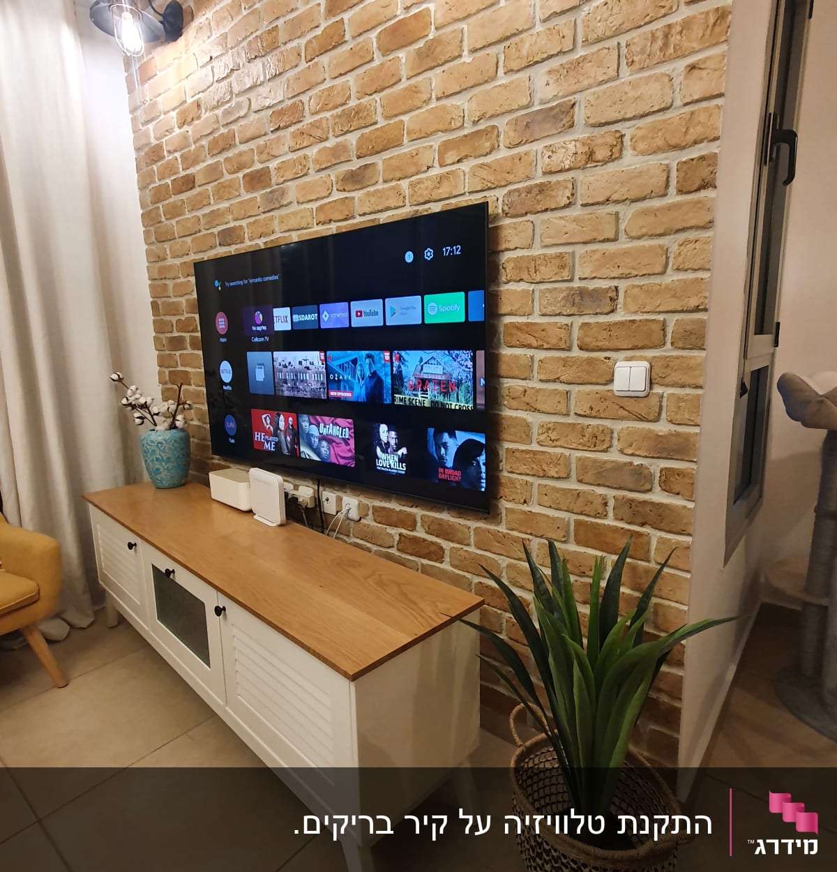 טלוויזיה תלויה על קיר לבנים עם תאורה